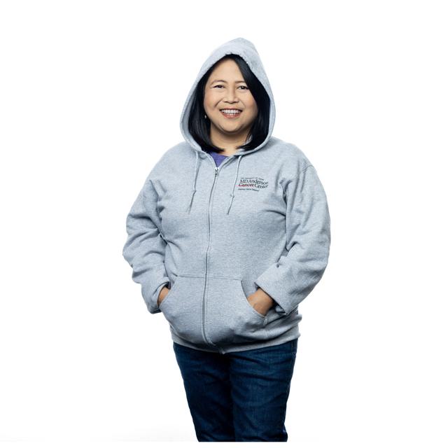 MD Anderson employee wearing a grey zippered hoodie with pockets, featuring the black MD Anderson logo on the chest area.
